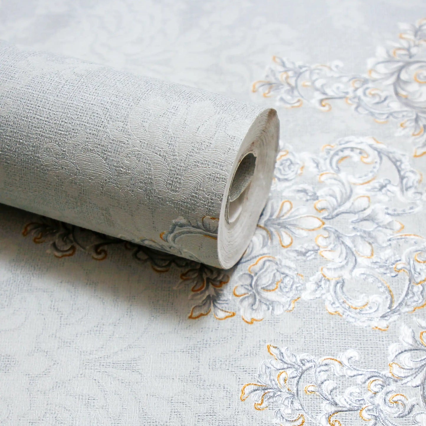 Roll of embossed wallpaper with intricate design on a plain background