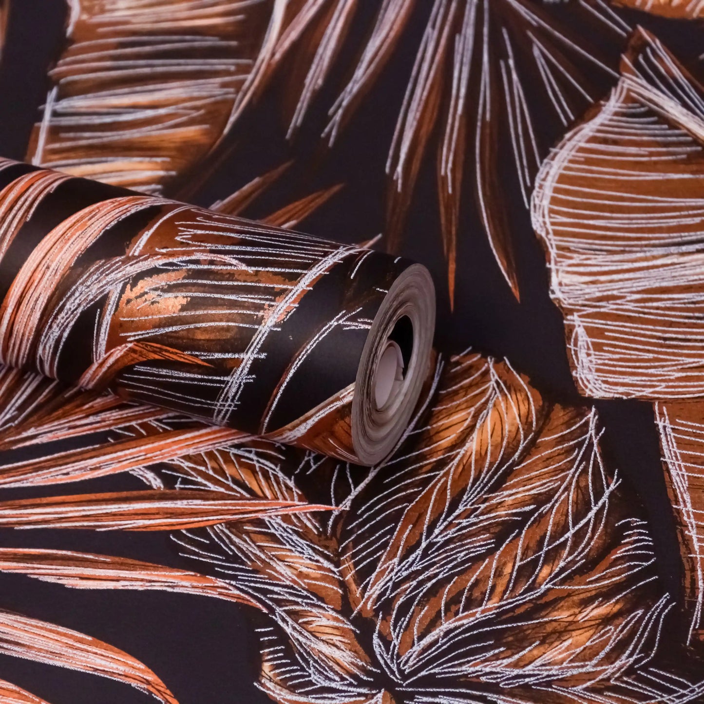 Roll of wallpaper with leaf pattern on a dark background