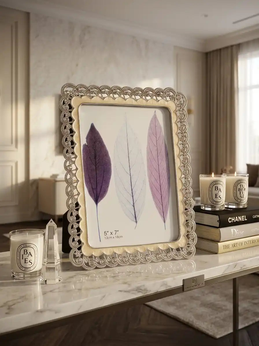 Decorative frame with pressed leaves on a marble surface with candles and books.