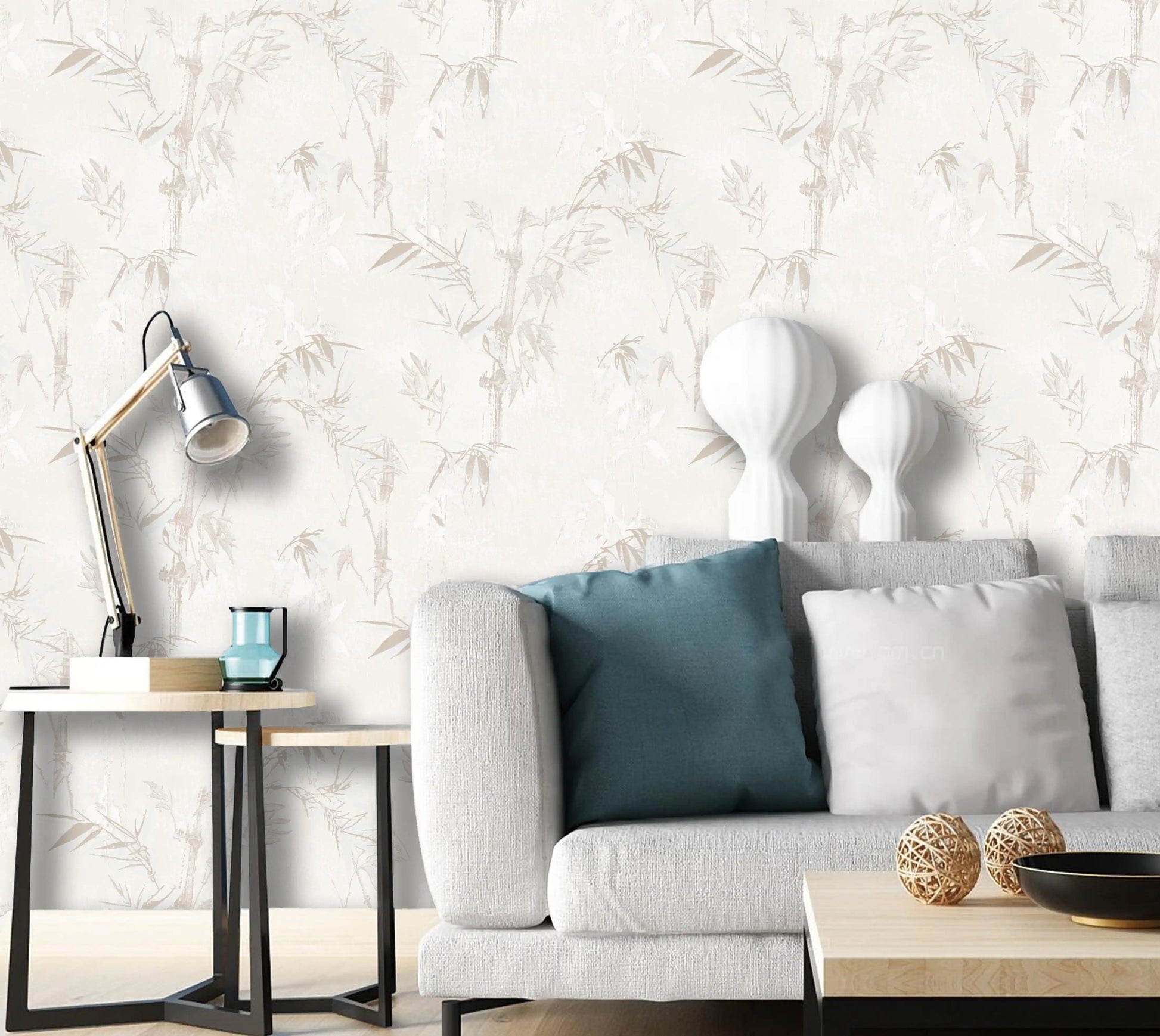 Modern living room with a gray sofa, decorative pillows, and a lamp against a leaf-patterned wall.