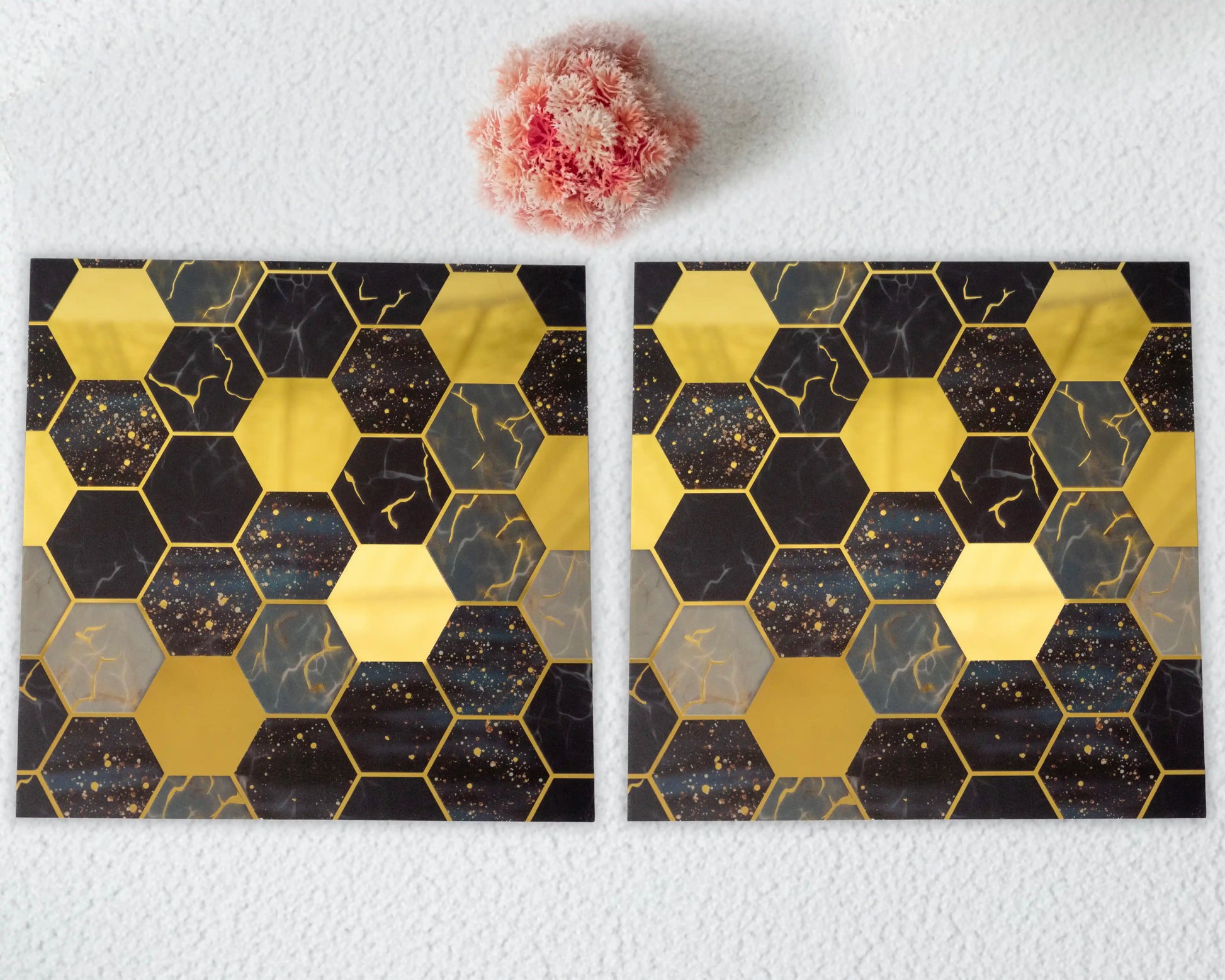 Two hexagonal patterned tiles on a white surface with a pink flower.
