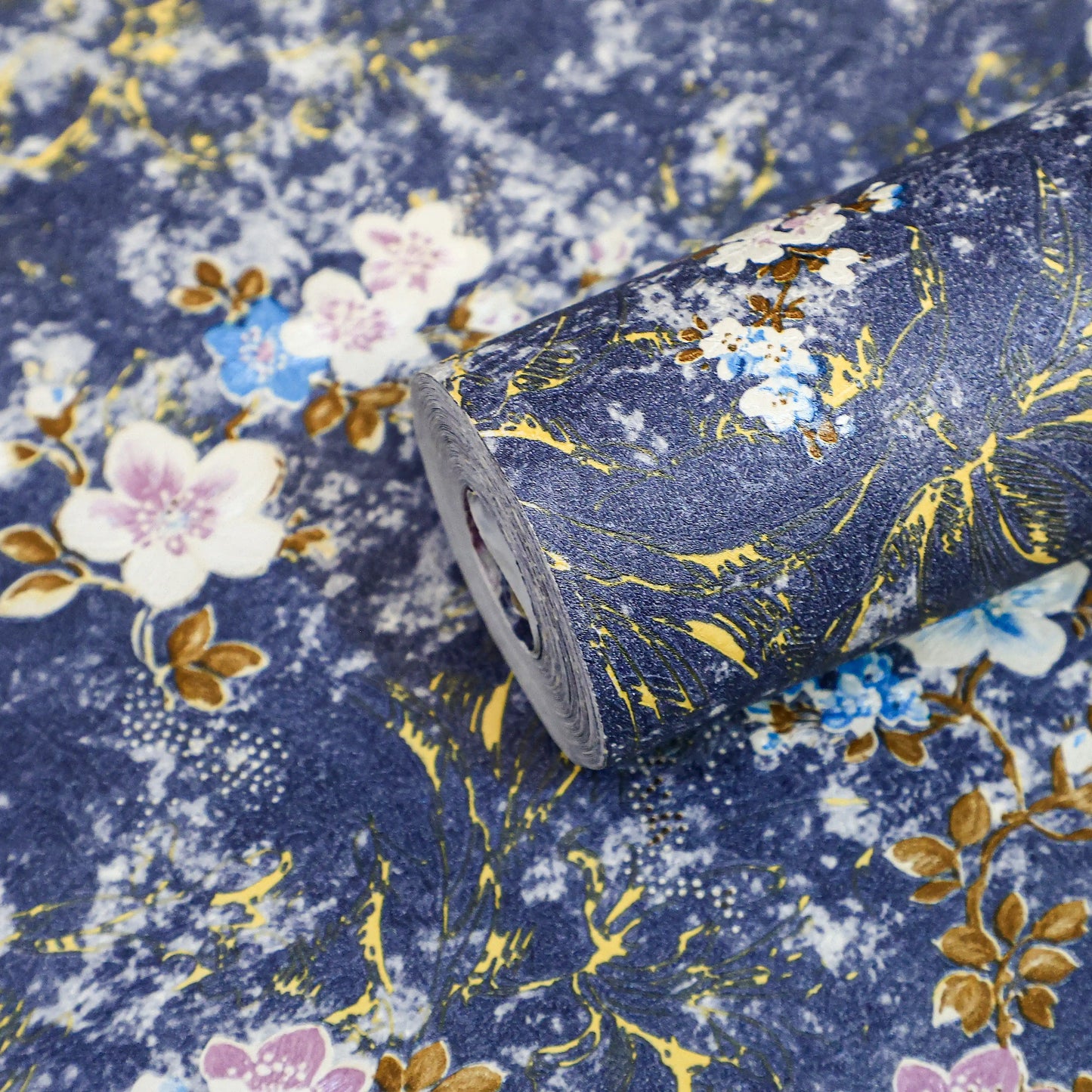 Roll of floral fabric with gold accents on a blue background