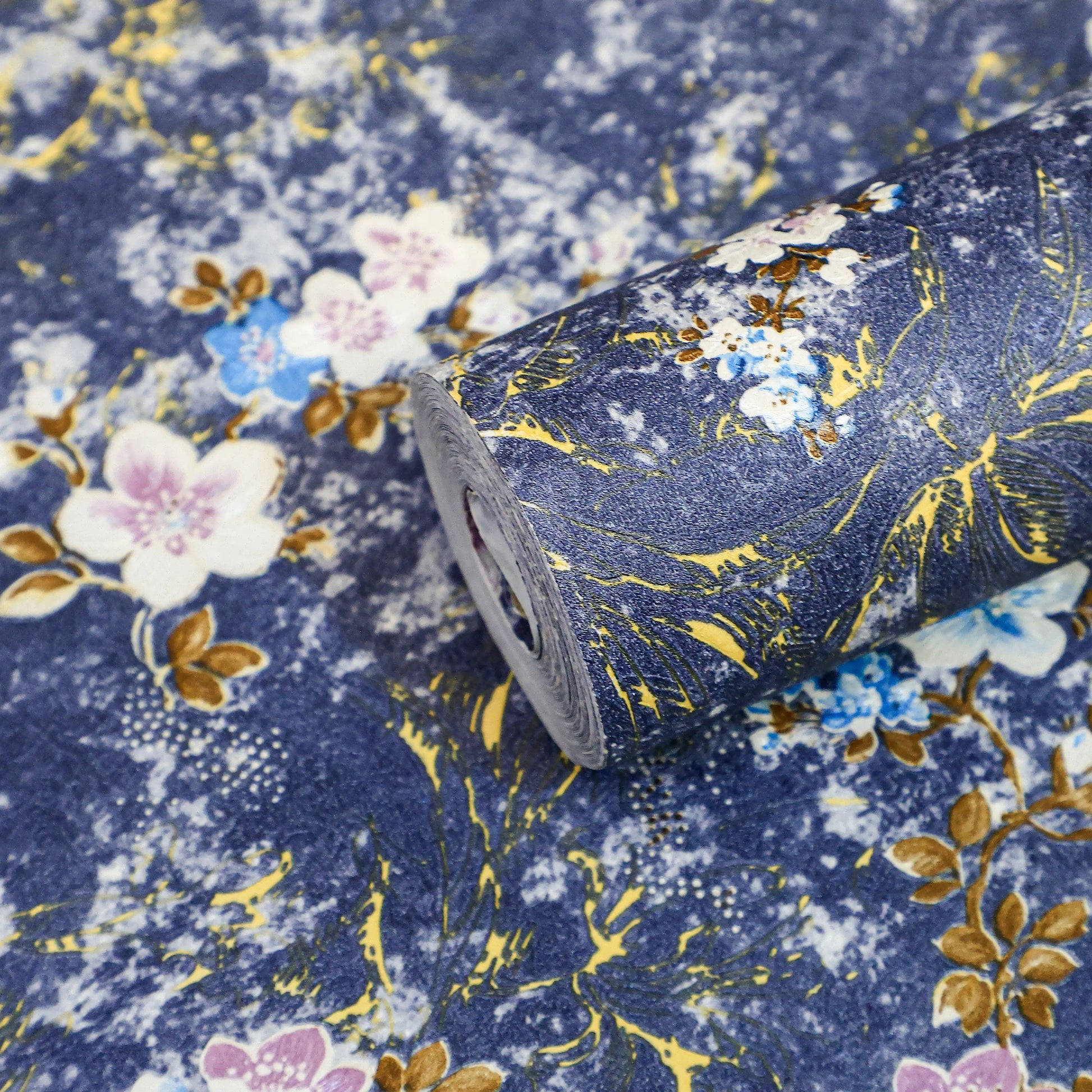 Roll of floral fabric with gold accents on a blue background