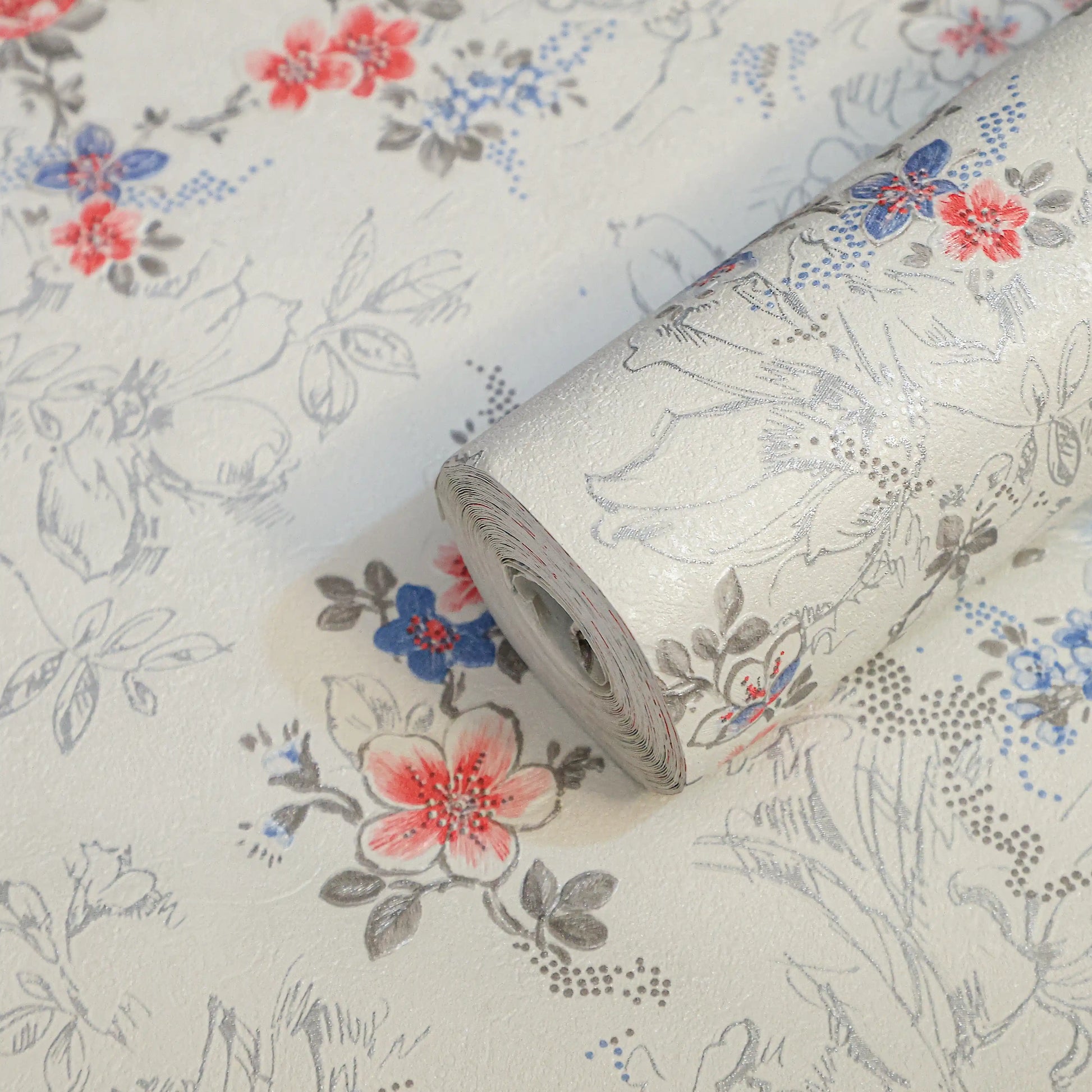 Roll of floral-patterned wallpaper with red, blue, and gray flowers on a light background