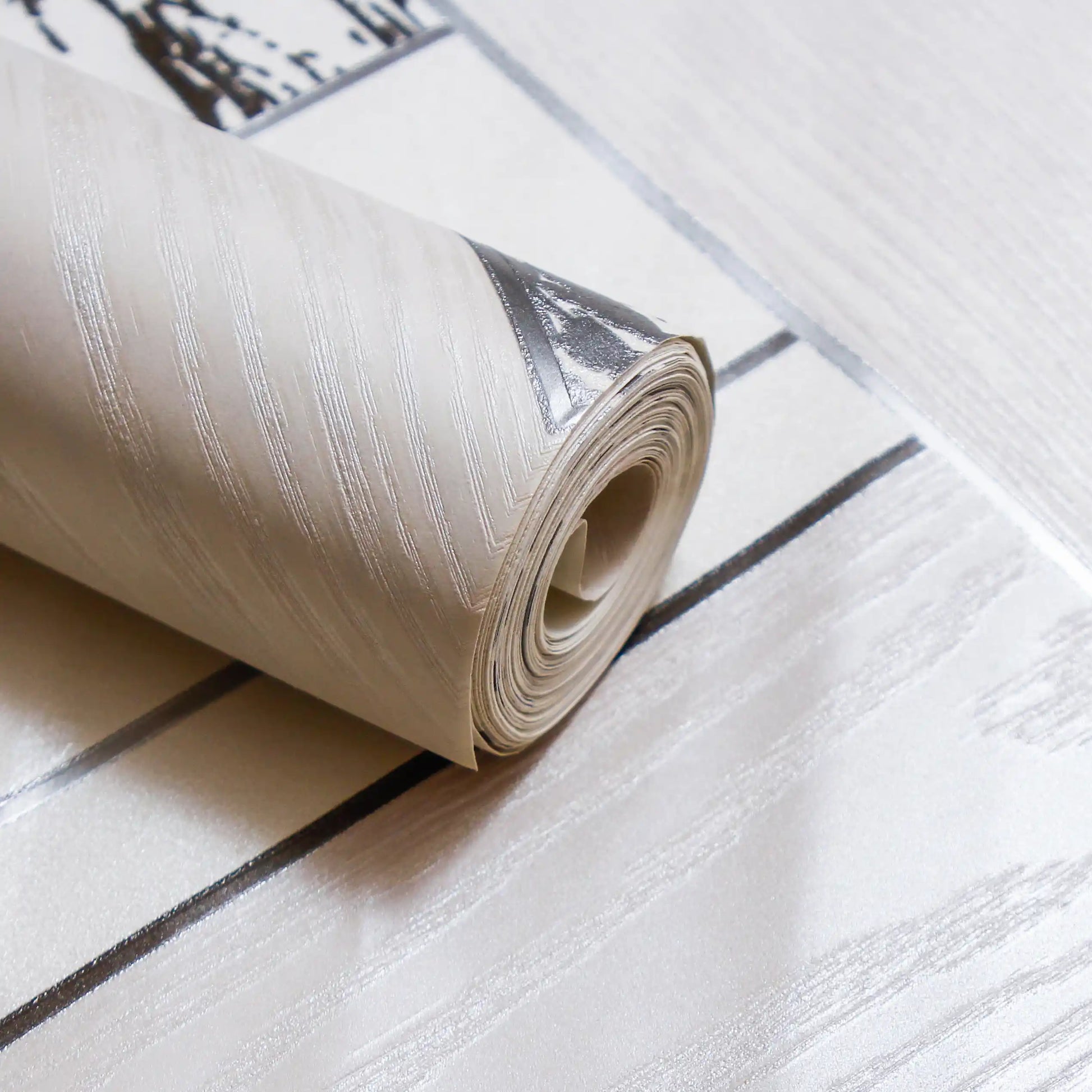 Roll of wallpaper on a white surface with black lines