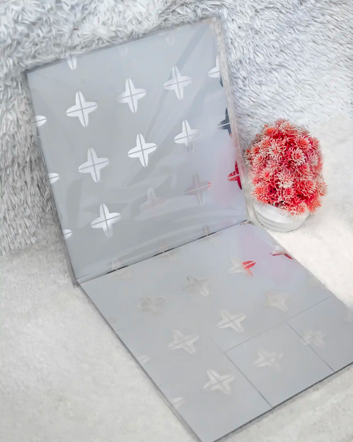 Gray fabric with star pattern on a textured surface with a red flower.