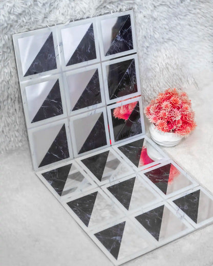 Black and white triangular tile pattern on a textured surface with pink flowers.