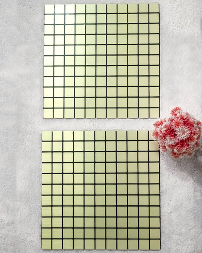 Two square tiles with grid pattern on a textured surface with a pink flower.