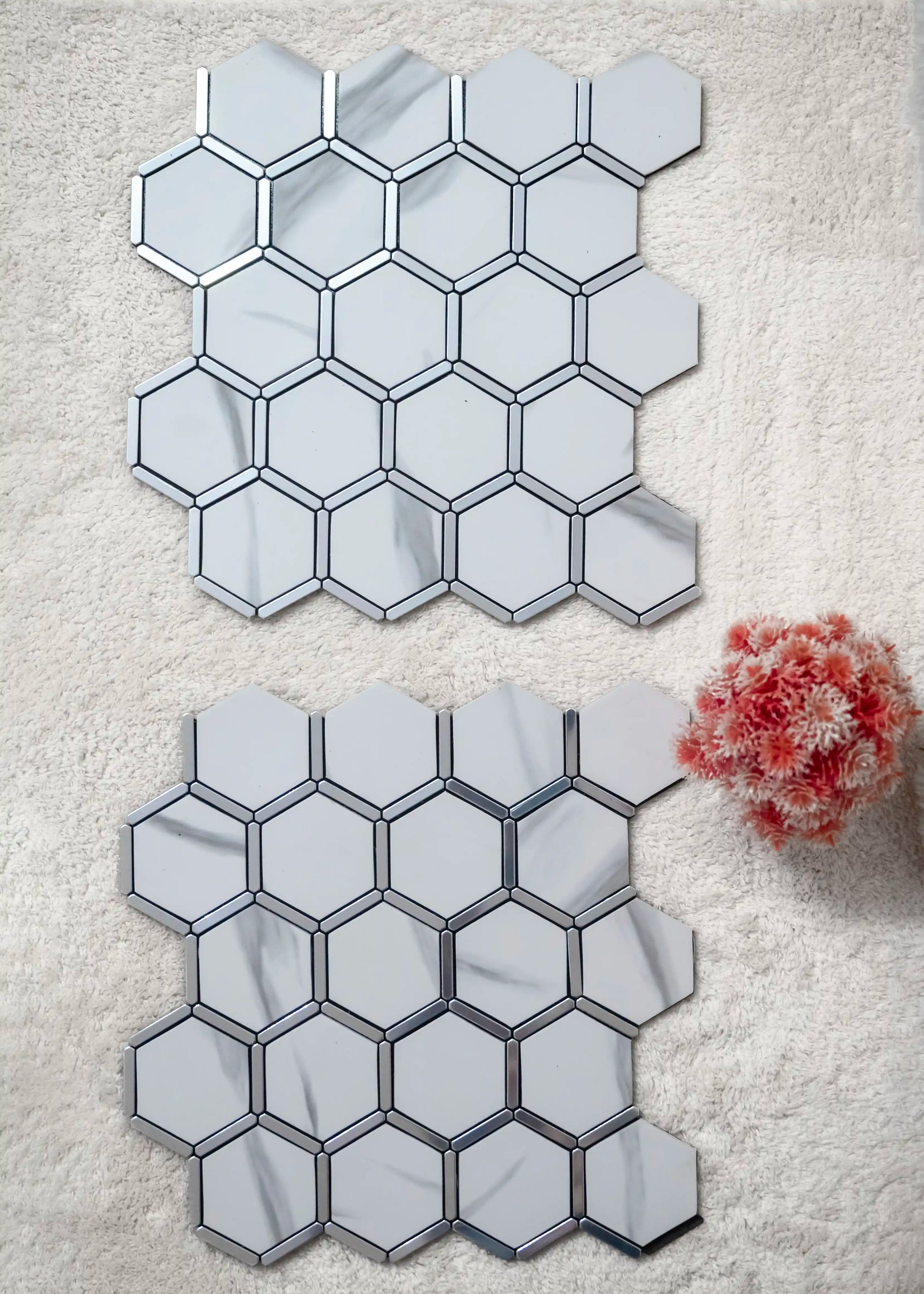 Hexagonal mirror tiles on a textured surface with a small plant.