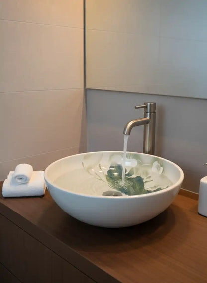 Bathroom sink with running water, towels, and a mirror.