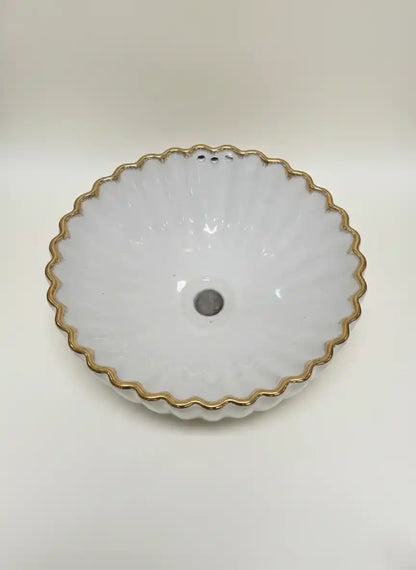 White ceramic bowl with gold rim on a white background