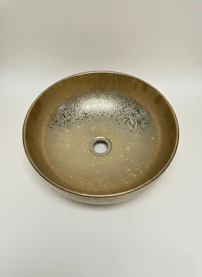Round ceramic sink with speckled glaze on a white background
