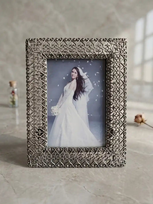 Decorative photo frame with a woman in a white dress inside, on a light surface.