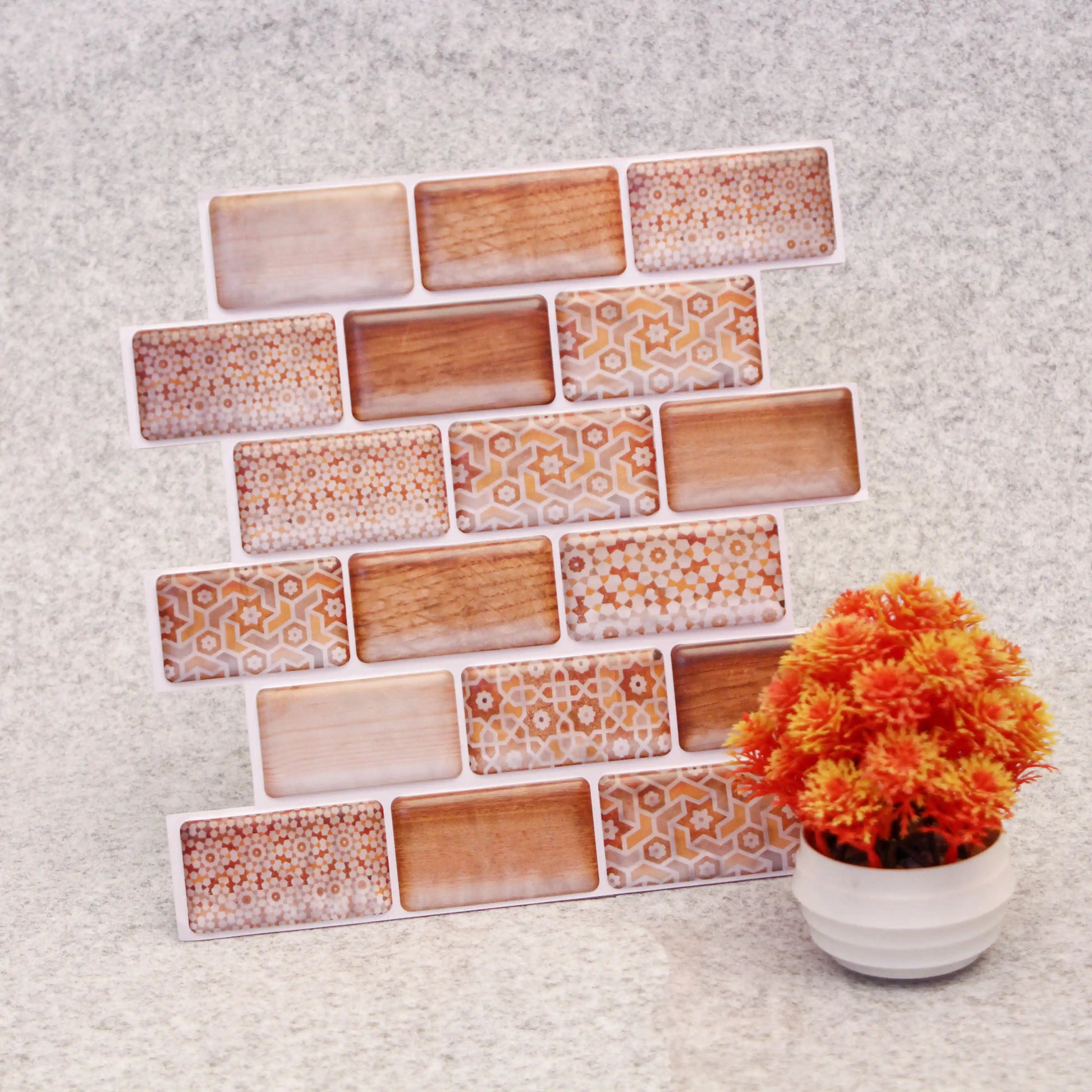 Set of decorative rectangular tiles with geometric patterns on a textured surface with a potted plant.