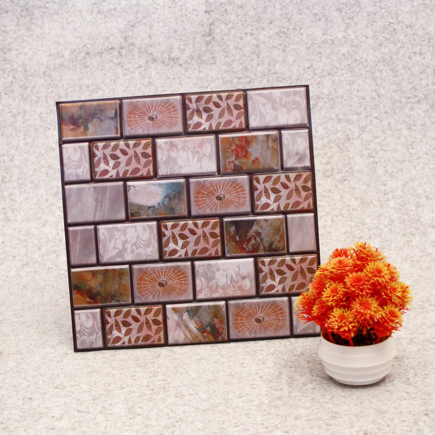 Decorative wall art with patterned tiles and a potted plant on a textured surface