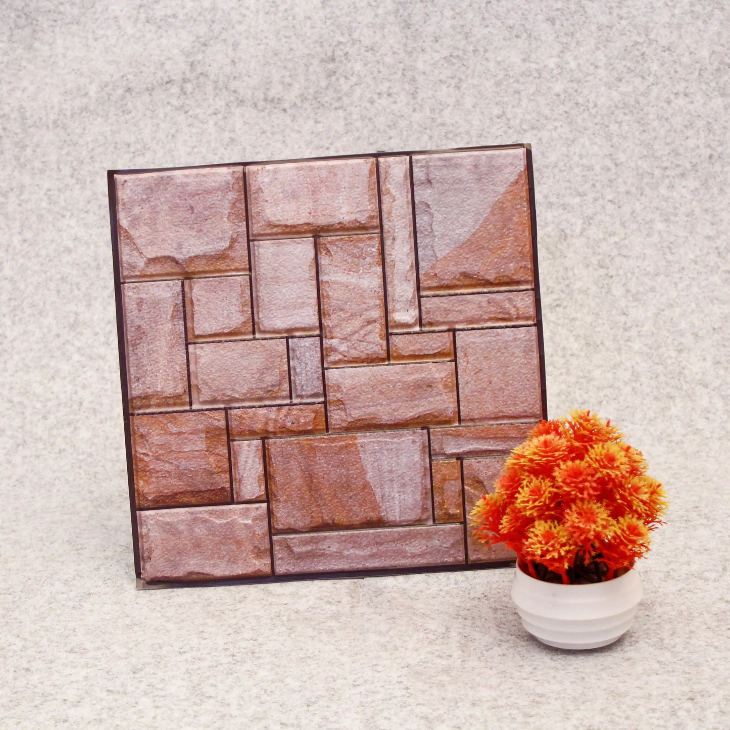 Decorative wall panel with stone pattern next to a potted plant on a textured surface