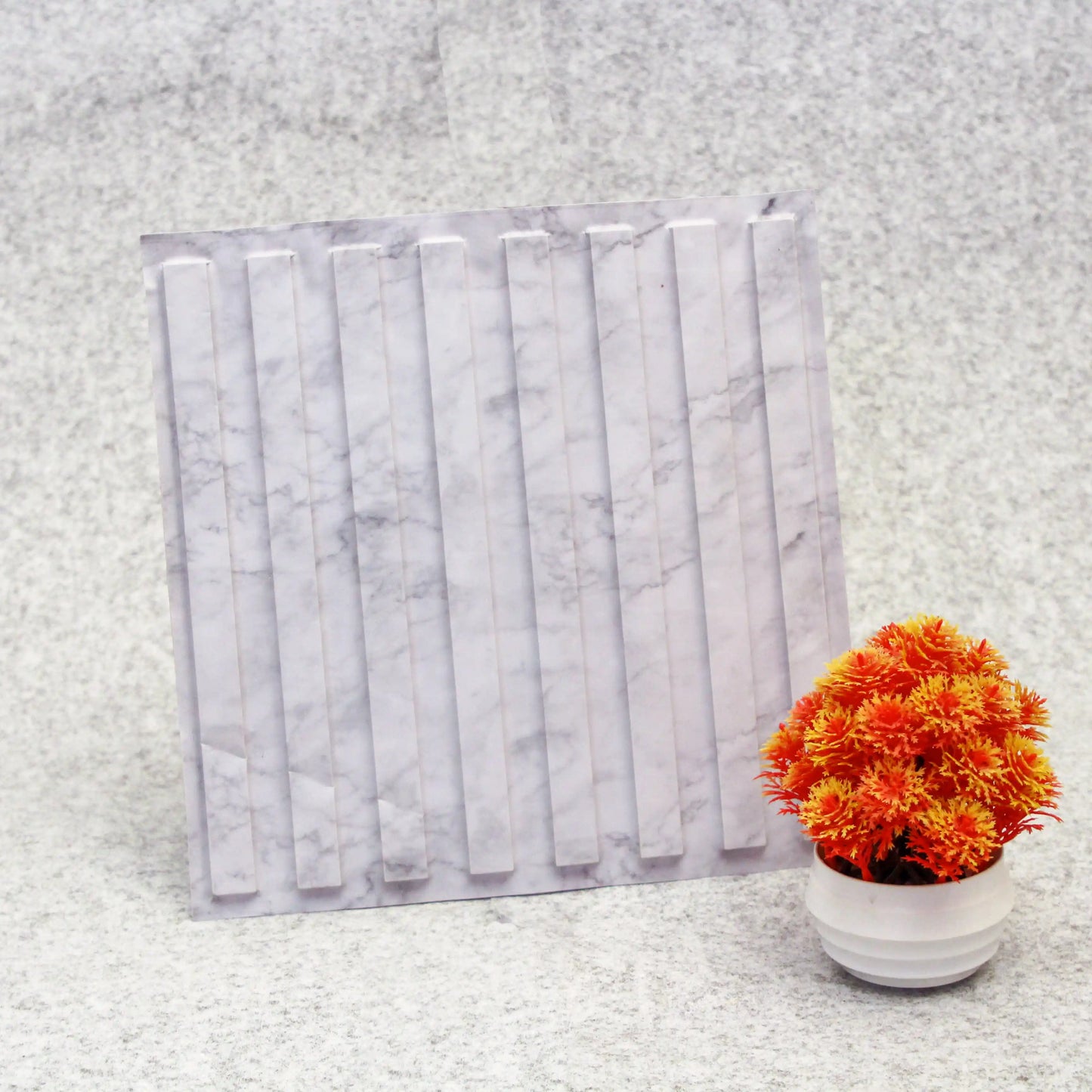 Marble-patterned product packaging with a small potted plant on a textured surface