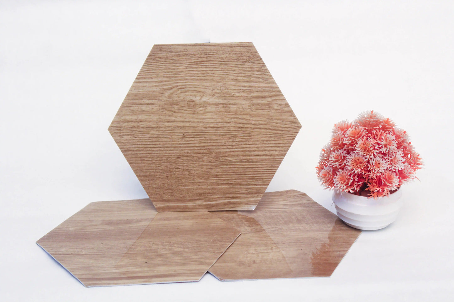 Hexagonal wooden tiles on a white surface with a small potted plant.