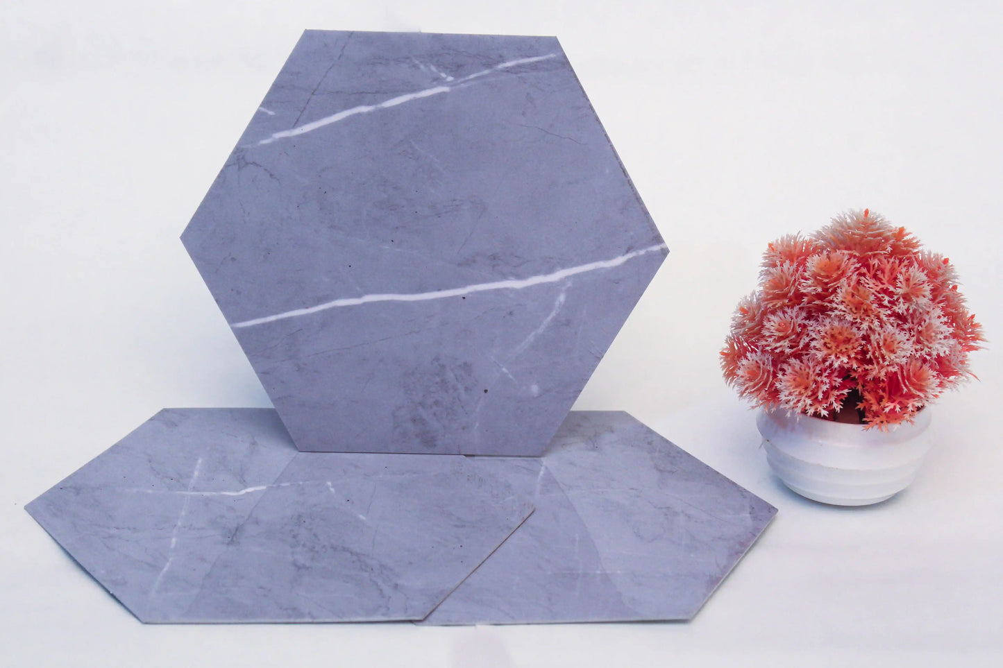 Hexagonal marble tiles on a white surface with a small potted plant.