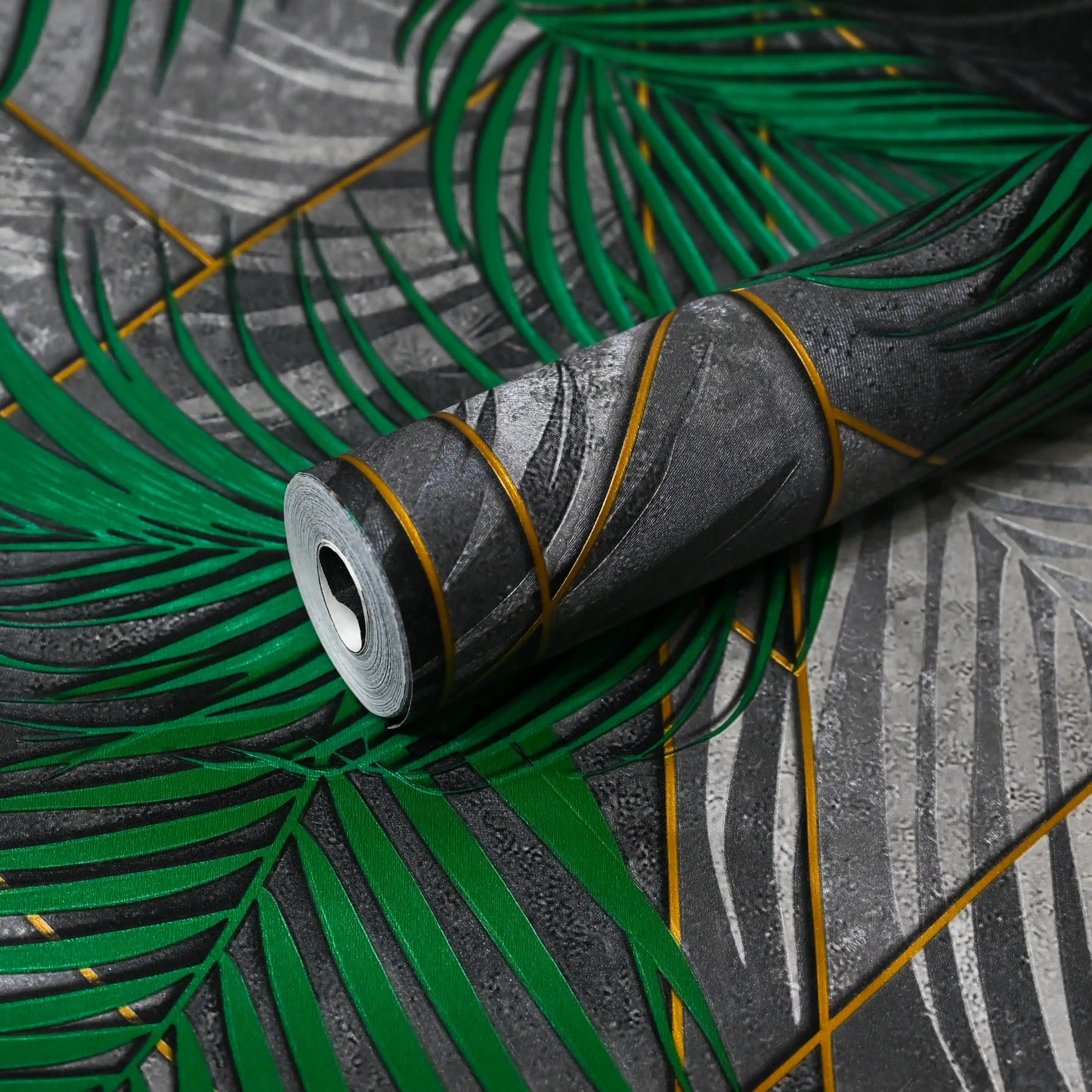 Roll of green and gray patterned wallpaper on a surface with leaf designs.