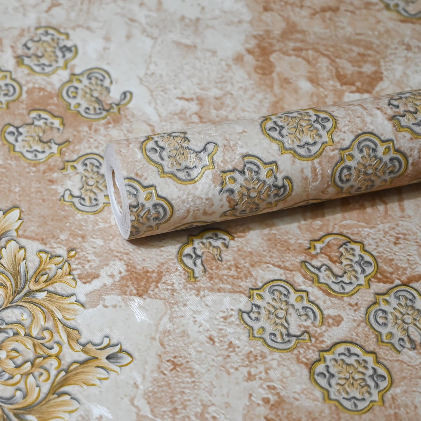 Roll of decorative wallpaper with intricate patterns on a textured surface
