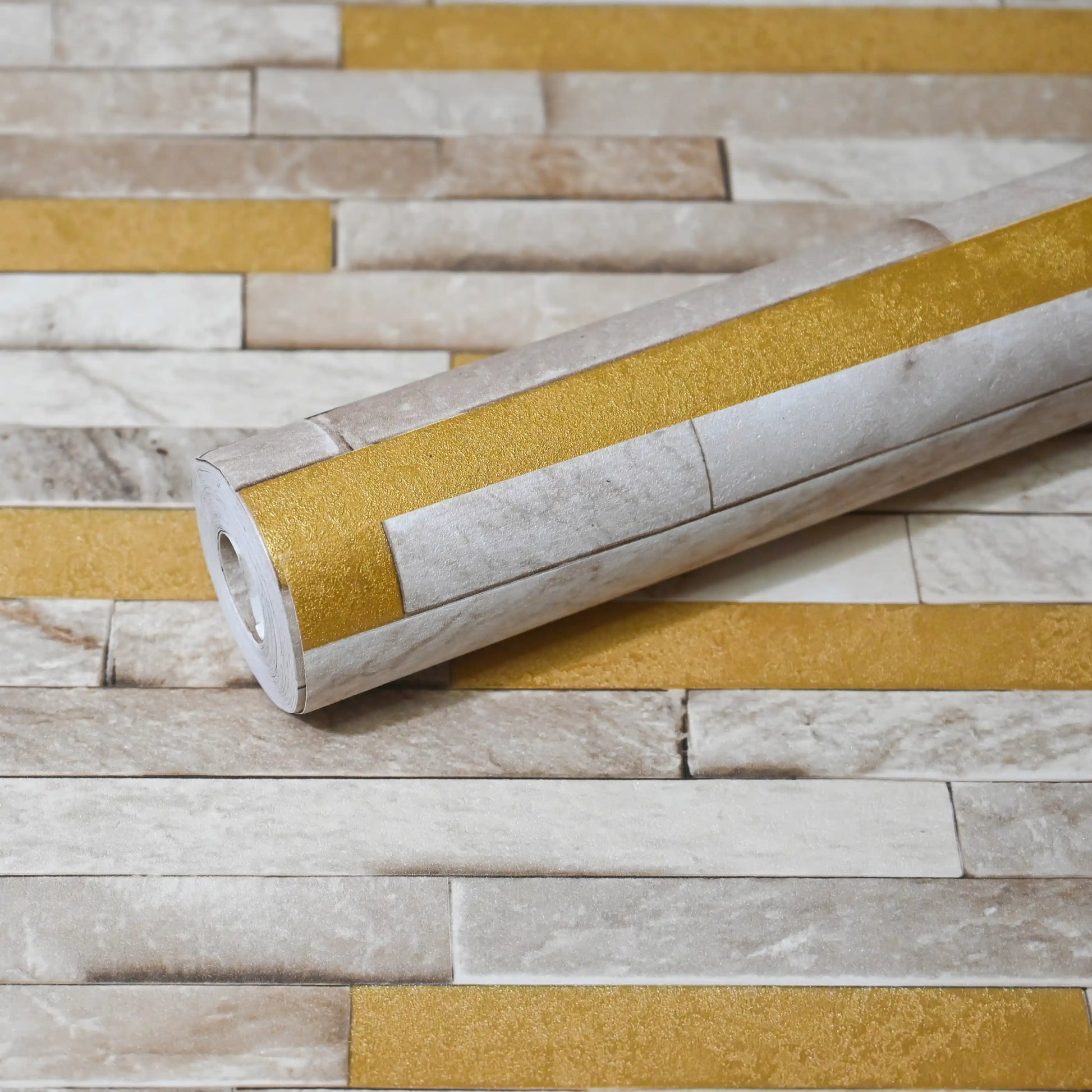 Roll of wallpaper with gold and beige pattern on a matching background