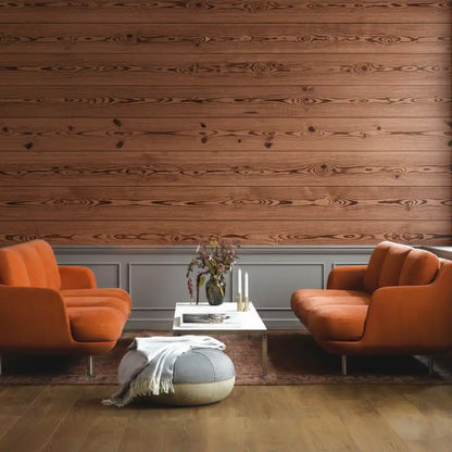 Two orange armchairs in a living room with wooden walls and a coffee table.
