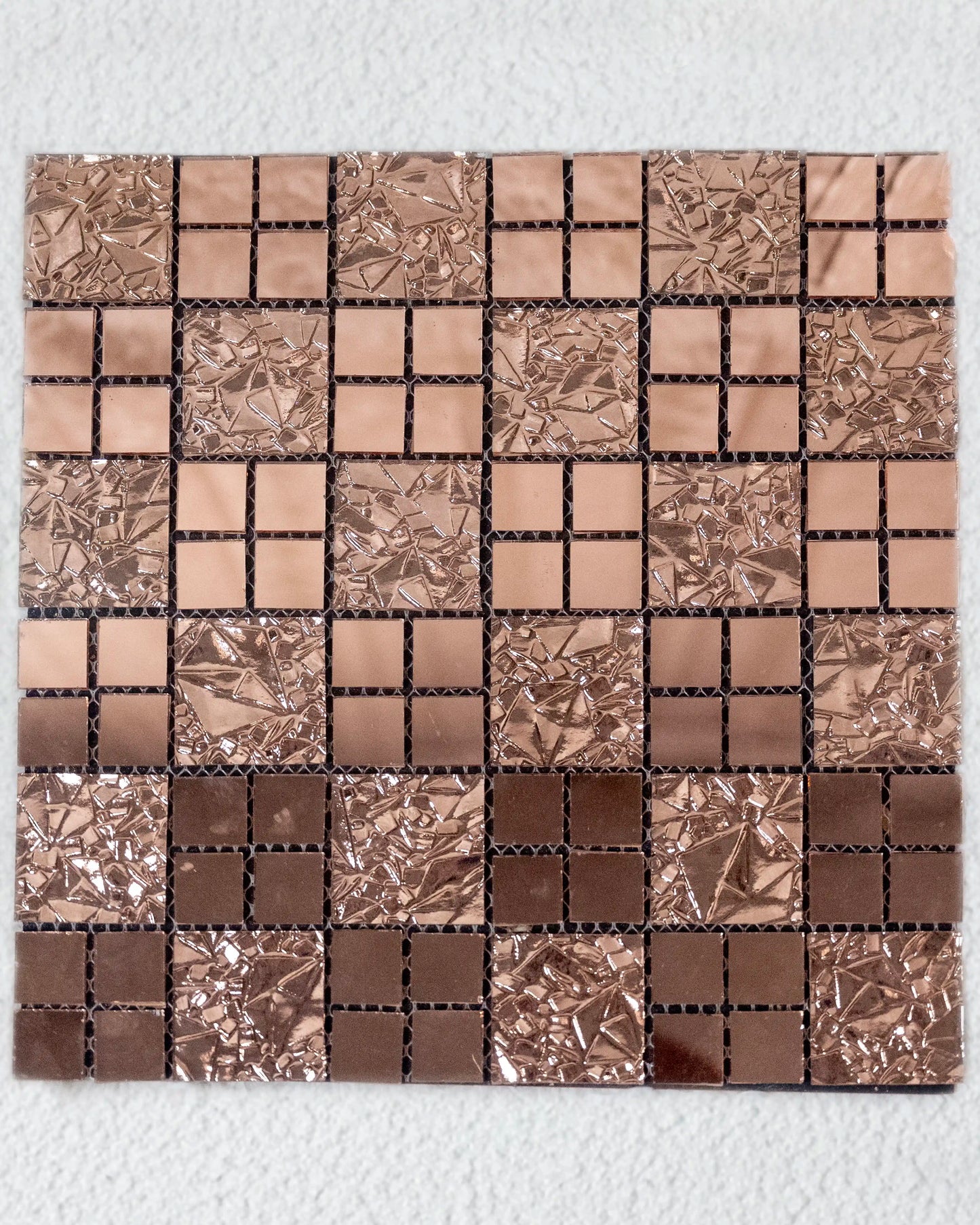 Mosaic tile sample with brown and silver squares on a white background