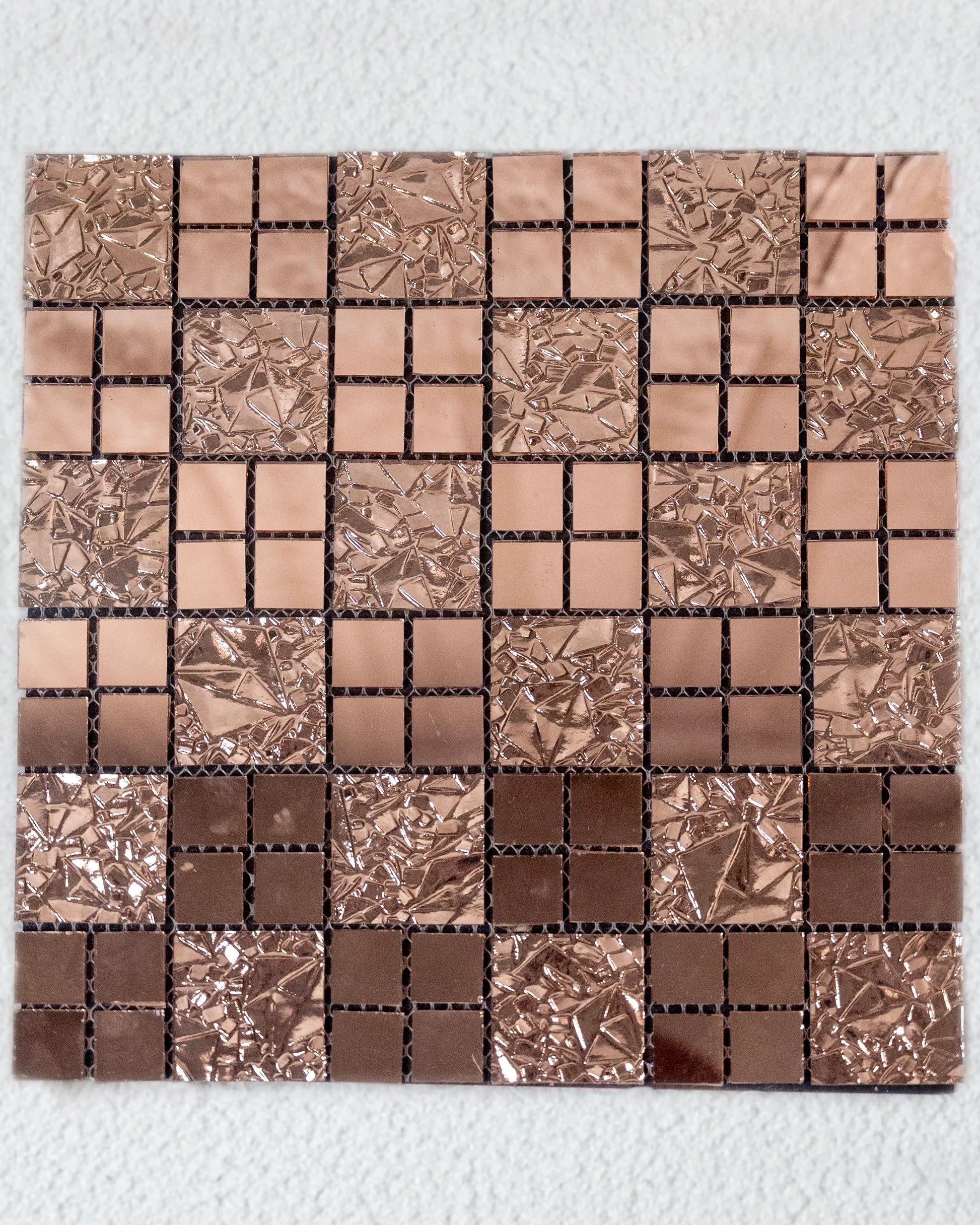 Mosaic tile sample with brown and silver squares on a white background