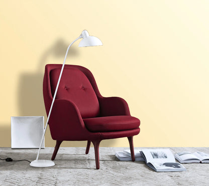 Red armchair with a white floor lamp against a yellow wall