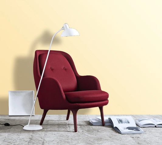 Red armchair with a white floor lamp against a yellow wall