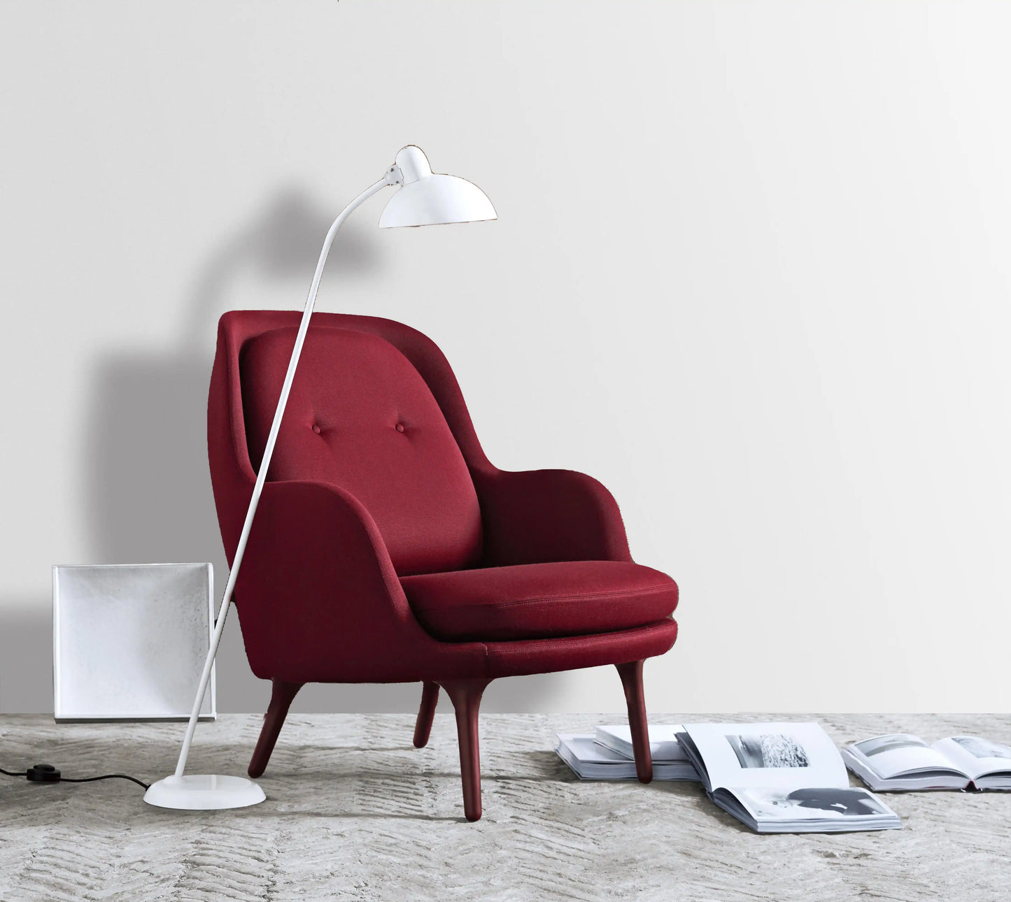 Red armchair with a white floor lamp on a light wooden floor.