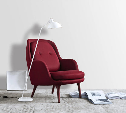 Red armchair with a white floor lamp on a light wooden floor.