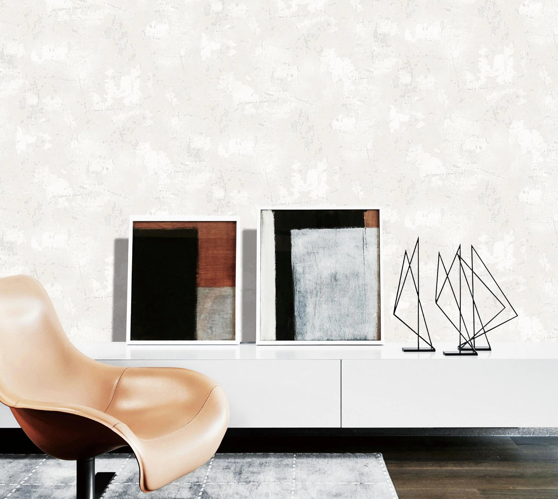 Modern interior with a beige chair, abstract sculptures, and framed art on a white wall.