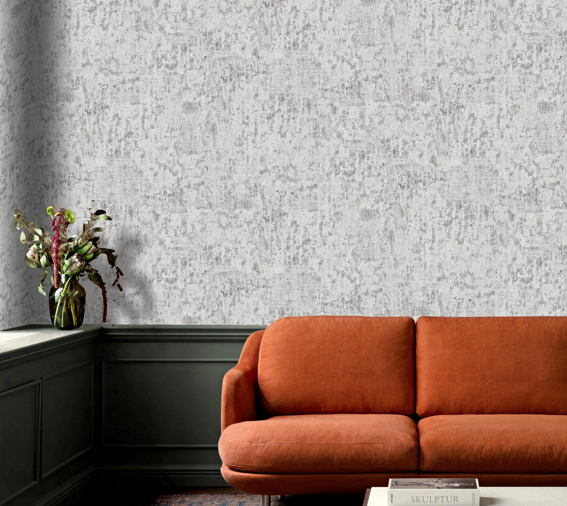 Orange sofa in a room with textured gray wallpaper and a vase of flowers on a shelf.