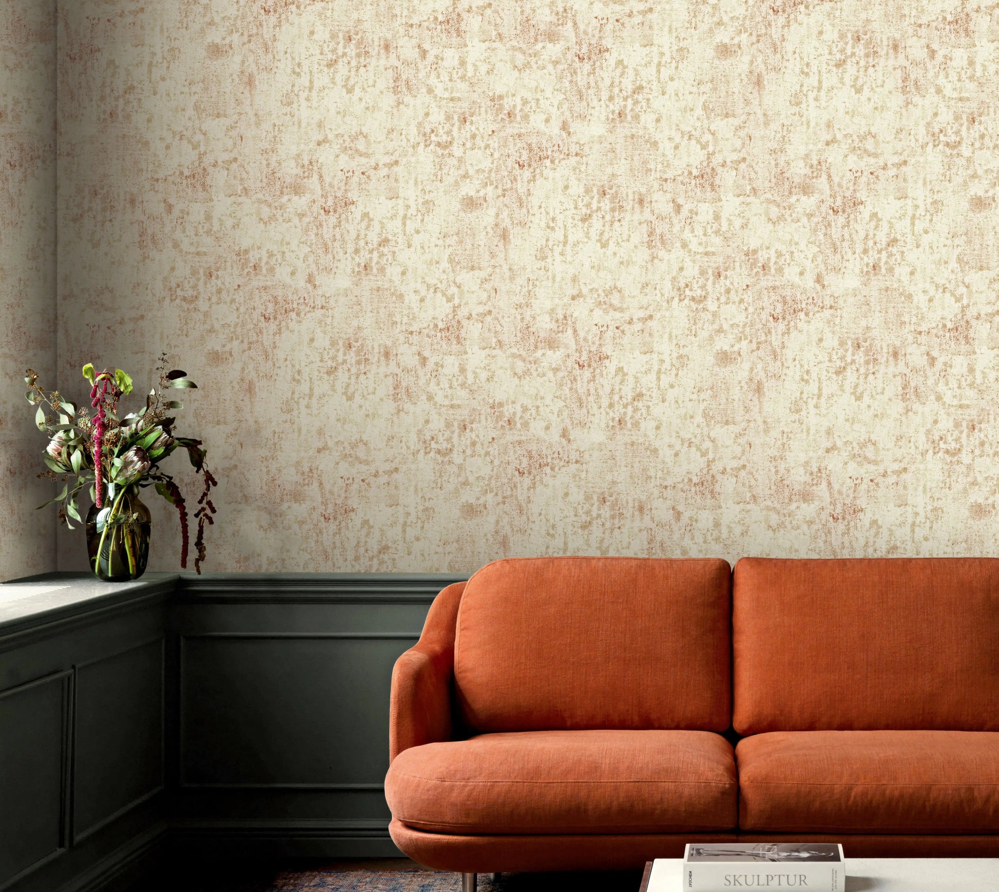 Orange sofa in a room with textured beige wall and decorative plant.