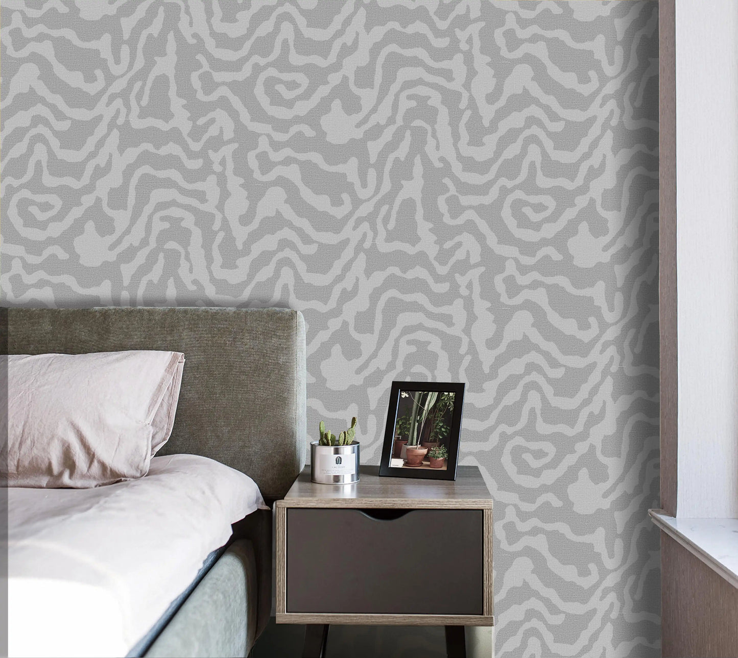 Bedroom with patterned wallpaper, bed, and nightstand.