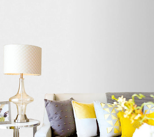 Living room with a couch featuring colorful pillows, a lamp, and a vase with flowers on a white background.