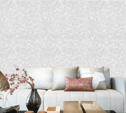 Living room with a gray sofa, decorative pillows, and a vase against a patterned wall.