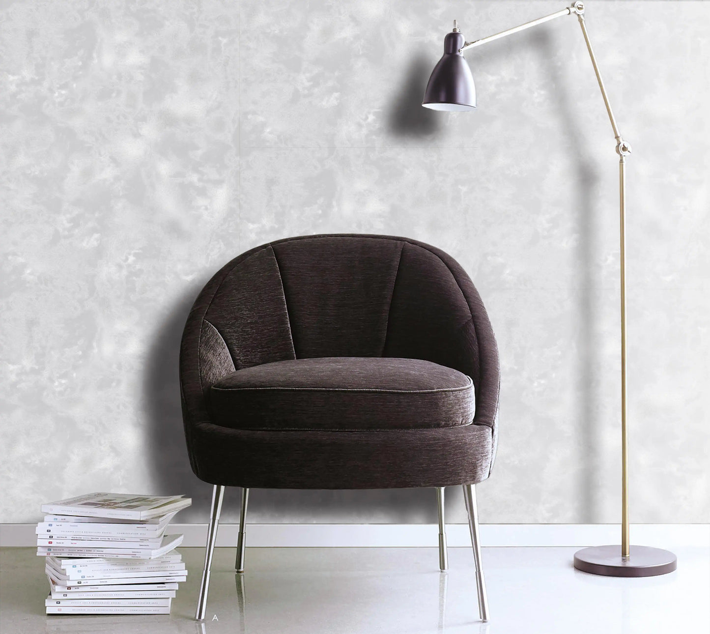 Brown armchair with a floor lamp and books against a light gray wall.