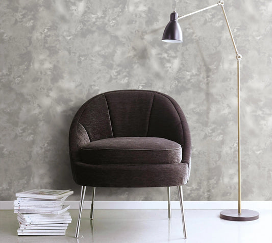 Brown armchair with a stack of books against a gray textured wall.