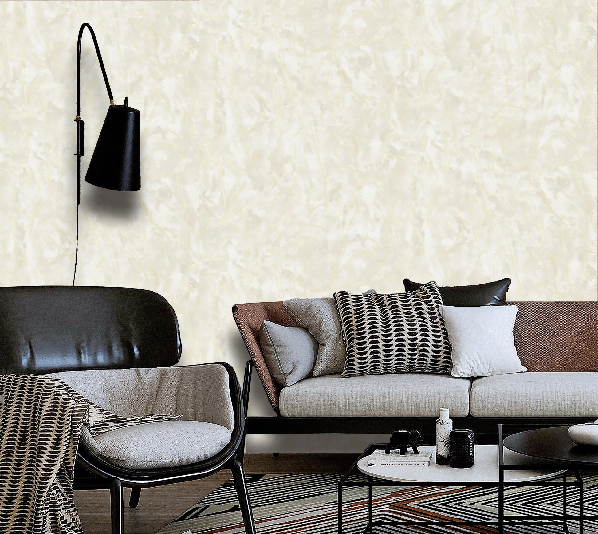 Modern living room with a sofa, chair, and wall lamp against a textured white wall.