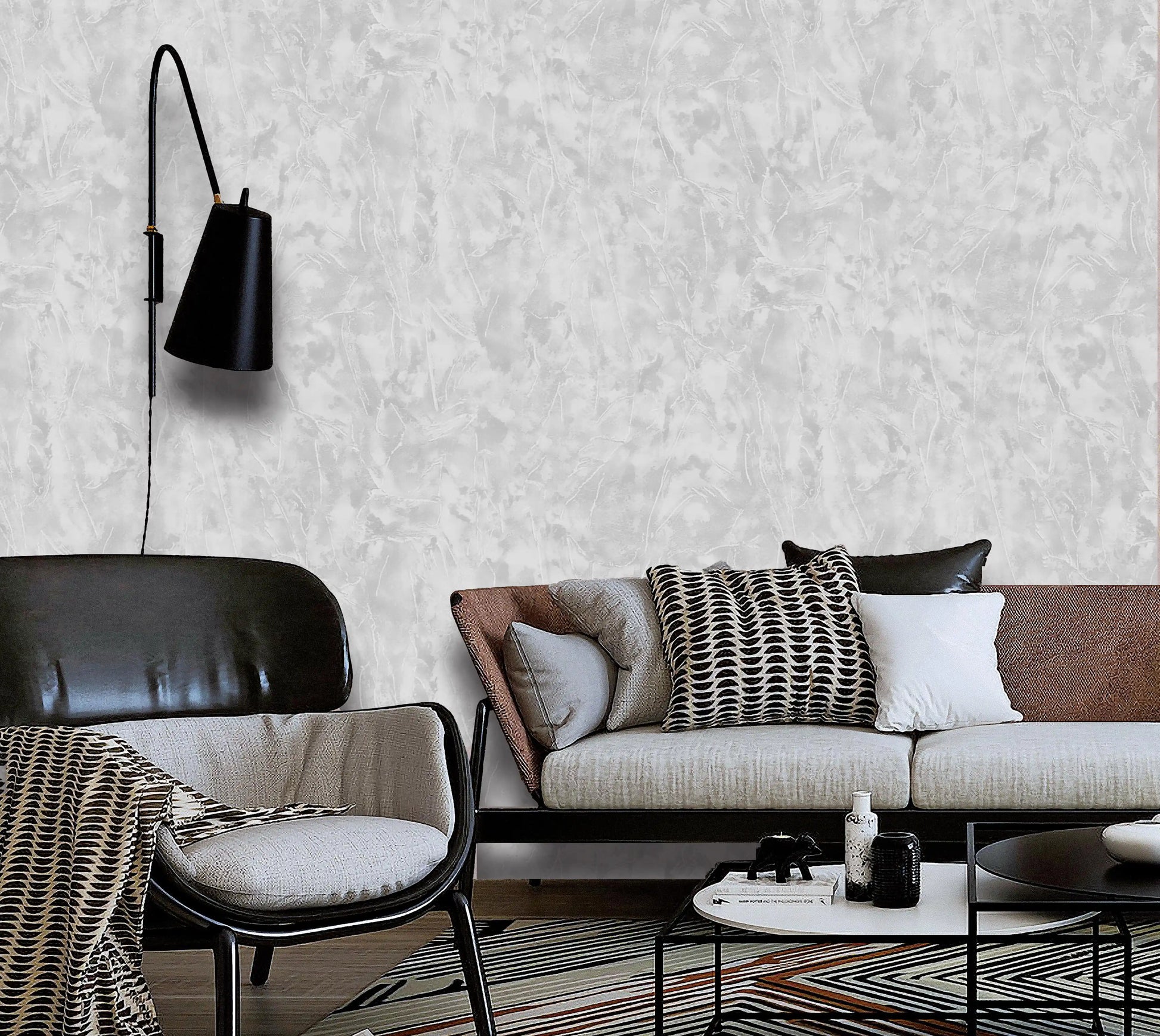 Modern living room with a sofa, chair, and wall lamp against a textured white wall.