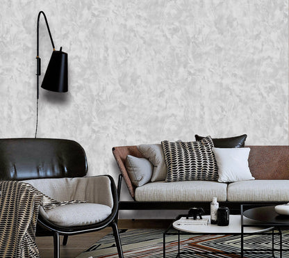 Modern living room with a sofa, chair, and wall lamp against a textured white wall.