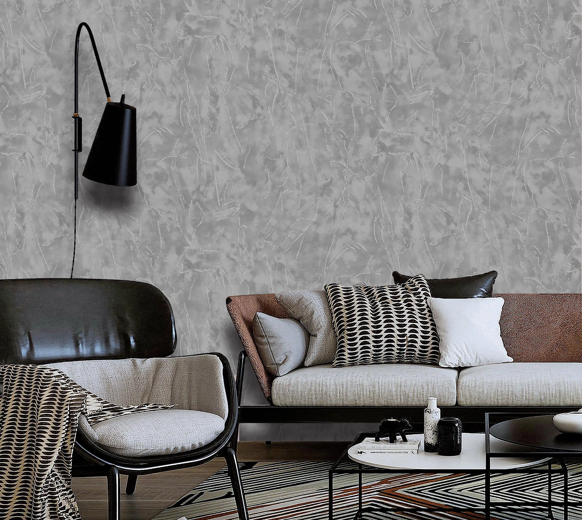 Modern living room with a gray textured wall, brown sofa, and black armchair.